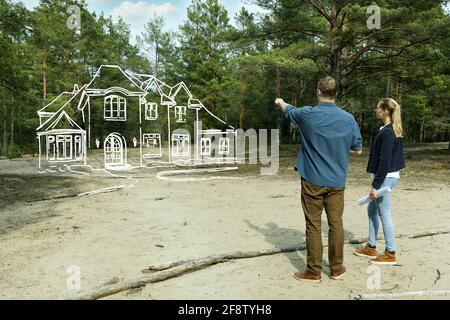 giovane coppia che guarda la loro famiglia sogno casa in foresta Foto Stock
