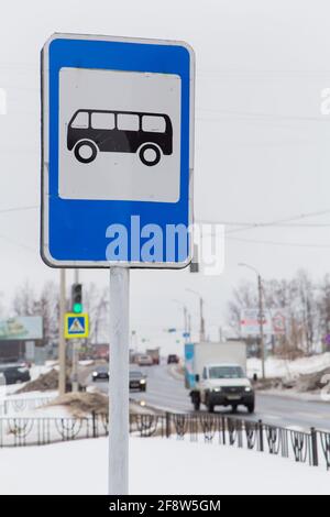 Un cartello stradale indica un luogo in cui fermare l'autobus, prendere e scendere i passeggeri. Sullo sfondo della strada e delle auto di passaggio. È inverno in città, la neve bianca si trova sulla strada. Foto Stock