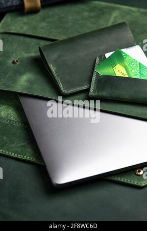 portafoglio verde, custodia per laptop in vera pelle e porta carte di credito sono sul tavolo. Vista dall'alto Foto Stock