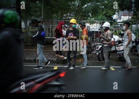 Giacarta, DKI Jakarta, Indonesia. 15 Aprile 2021. I residenti si accodano applicando la regola della distanza per ottenere il takjil libero sulle strade del centro di Giacarta, giovedì (04/15/2021). I residenti sono obbligati ad accodarsi applicando una distanza di due metri per prevenire la diffusione del coronavirus. Eeveryday la commissione fornisce 400-600 pacchetti takjil gratuitamente che sono donazioni da residenti e società nella regione. Credit: Muhammad Zaenuddin/ZUMA Wire/Alamy Live News Foto Stock