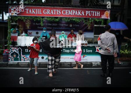 Giacarta, DKI Jakarta, Indonesia. 15 Aprile 2021. I residenti si accodano applicando la regola della distanza per ottenere il takjil libero sulle strade del centro di Giacarta, giovedì (04/15/2021). I residenti sono obbligati ad accodarsi applicando una distanza di due metri per prevenire la diffusione del coronavirus. Eeveryday la commissione fornisce 400-600 pacchetti takjil gratuitamente che sono donazioni da residenti e società nella regione. Credit: Muhammad Zaenuddin/ZUMA Wire/Alamy Live News Foto Stock