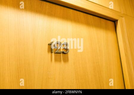 La porta della camera nell'hotel con il numero 123. Porta in legno chiusa nell'hotel. Foto Stock