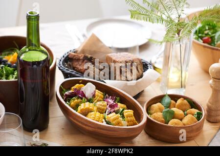 Primo piano di diversi piatti e bottiglia di vino da servire cena sul tavolo da pranzo Foto Stock