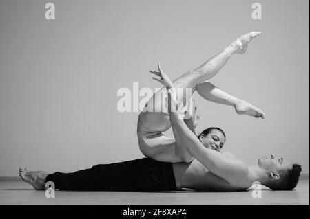 Posa pesante del circo. Un giovane ha una donna flessibile. Due acrobati o ballerini che si posano su uno sfondo bianco. Un paio di ginnasti esegue l'arte Foto Stock