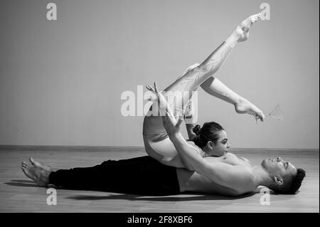 Posa pesante del circo. Un giovane ha una donna flessibile. Due acrobati o ballerini che si posano su uno sfondo bianco. Un paio di ginnasti esegue l'arte Foto Stock