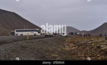 Punto di partenza dell'escursione a un vulcano recentemente eruttato vicino al monte Fagradalsfjall con persone che camminano e auto di polizia sulla strada in un giorno nuvoloso. Foto Stock