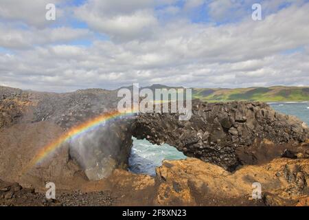 Arcobaleno e arco naturale, eroso nero formazione di basalto a Capo Dyrhólaey / Cape Portland vicino Vík í Mýrdal, Islanda Foto Stock