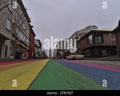 Vista della vuota strada arcobaleno nel centro di Reykjavik, dedicata al Reykjavik Pride Gay Festival, con la famosa chiesa di Hallgrímskirkja in inverno. Foto Stock