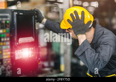 tecnico lavoratore inesperto di servizio uomo confuso nervoso e stressante a riparare e far funzionare il problema della macchina rotta in fabbrica Foto Stock