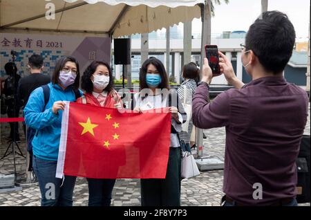 Hong Kong, Hong Kong, Cina. 15 Aprile 2021. I cittadini patriottici (alcuni in posa aperta con la Bandiera Cinese) approfittano di alcuni degli eventi che celebrano la prima Giornata Nazionale dell'Educazione sulla sicurezza presso il Centro Culturale Promenade Tsim Sha Tsui, Hong Kong. Con l'obiettivo di celebrare l'introduzione delle leggi sulla sicurezza nazionale a Hong Kong alle 23:00 30 giugno 2020, questa celebrazione annuale si terrà ogni anno il 15 aprile. Le persone hanno foto di se stesse stampate e attaccate ad un bordo che crea un'immagine pro NSL e slogan. Credit: Jayne Russell/ZUMA Wire/Alamy Live News Foto Stock