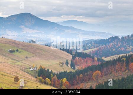 Paesaggio montano autunnale, sagome di montagna in nebbia, cielo scuro. Ucraina, Carpazi. Foto Stock