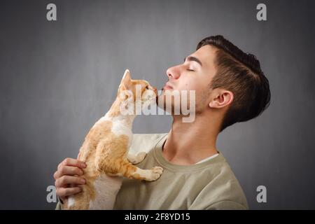 Uomo che tiene e baciare muso cute Devon rex gatto Foto Stock