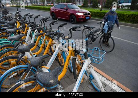 Pechino, Cina. 15 Aprile 2021. Un pedone cammina attraverso le biciclette che sono coperte di polvere. A Pechino, polvere, gale e pioggia appaiono allo stesso tempo. La polvere mescolata alla pioggia, ai pedoni esterni e ai veicoli ha causato molti problemi. (Foto di Sheldon Cooper/SOPA Images/Sipa USA) Credit: Sipa USA/Alamy Live News Foto Stock