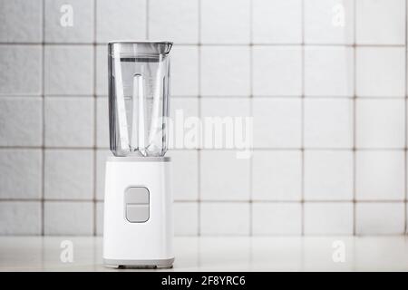Svuotare il frullatore elettrico in cucina per cocktail e cibi sani. Frullatore bianco sul tavolo con piastrelle da cucina leggere. Concetto minimo, spazio di copia Foto Stock