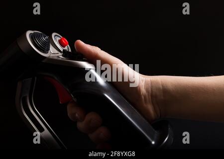 La mano del bambino gioca con un simulatore di velivolo a joystick, primo piano su sfondo nero. Foto Stock