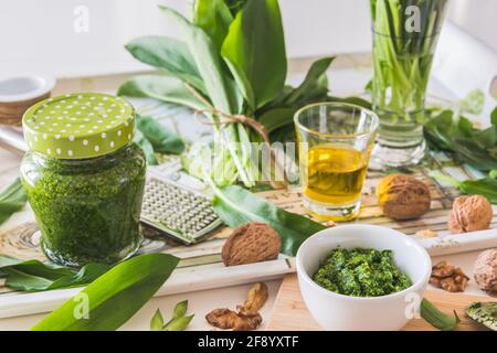 Pesto di aglio selvatico fatto in casa in una ciotola bianca e suo ingredienti su un vassoio su sfondo bianco Foto Stock