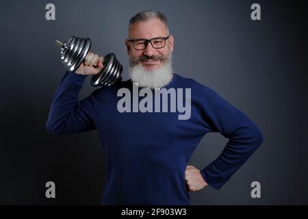 Uomo maturo bearded con manubri. Uomo con manubri durante l'esercizio. Sport, allenamento, fitness, stile di vita sano. Foto Stock