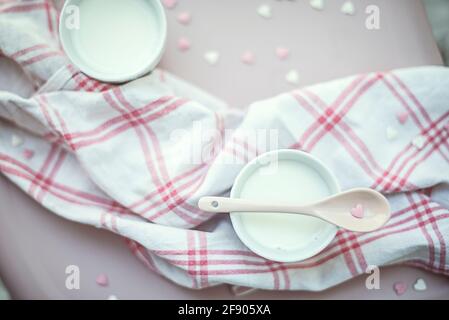 Vista dall'alto di una tazza di latte a forma di cuore cospargere le decorazioni sul tavolo e un tovagliolo Foto Stock