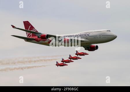 Virgin Atlantic Boeing 747 Jumbo Jet aereo volare in formazione con RAF Royal Air Force frecce rosse display team getti di fumo di tallonamento. Airshow. Compagnia aerea Foto Stock