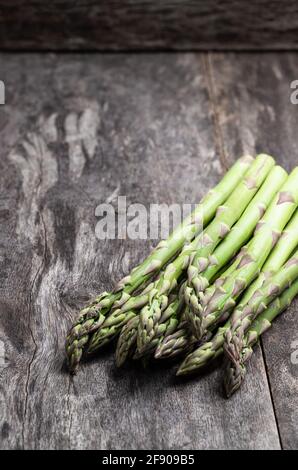 Asparagi crudi freschi verdi su tavola rustica in legno Foto Stock