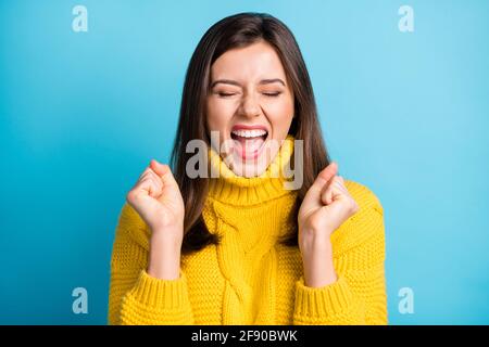 Primo piano ritratto di bella estatica allegra fortunata ragazza fan tenuta i pugni sono isolati su uno sfondo di colore blu brillante Foto Stock