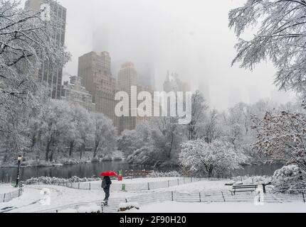 Persona irriconoscibile che cammina nel parco innevato del centro Foto Stock
