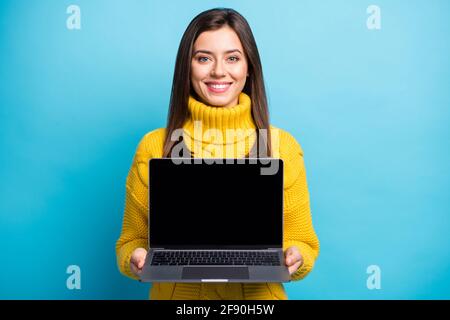 Ritratto di bella ragazza allegra abile che tiene in mano il computer portatile visualizzazione dello schermo isolato su uno sfondo di colore blu lucido Foto Stock