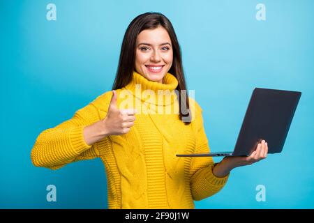 Ritratto di bella ragazza allegra che tiene in mano laptop mostrando pubblicità thumbup isolata su sfondo di colore blu brillante Foto Stock