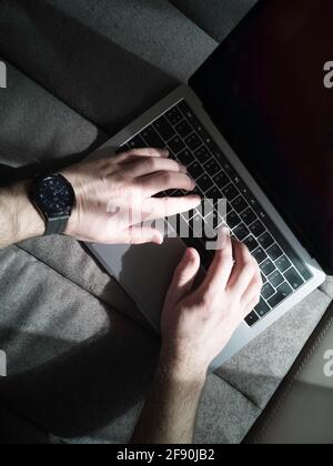 Le mani dell'uomo sulla tastiera del computer portatile. Vista dall'alto. Foto Stock