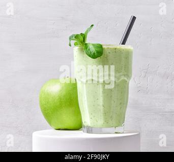bicchiere di frullato verde e mela su supporto bianco Foto Stock
