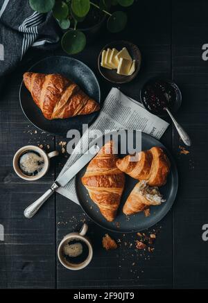 Piatti di croissant con caffè e marmellata sul tavolo nero dall'alto. Foto Stock