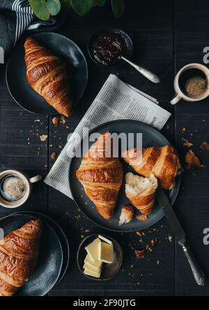 Piatti di croissant con caffè e marmellata sul tavolo nero dall'alto. Foto Stock