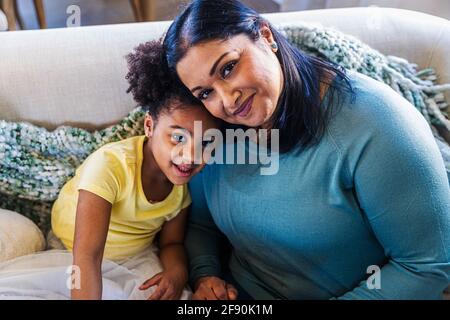 Ritratto di sorridente ragazza carina con nonna sul divano a. casa Foto Stock