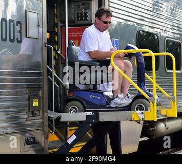 Bartlett, Illinois, Stati Uniti. Un passeggero disabile esce da un treno metropolitano di andata Metra dopo essere arrivato alla stazione ferroviaria per pendolari. Foto Stock