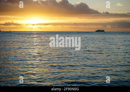 La nave da crociera naviga di fronte al tramonto a Waikiki Beach, Honolulu, Oahu, Hawaii, USA Foto Stock