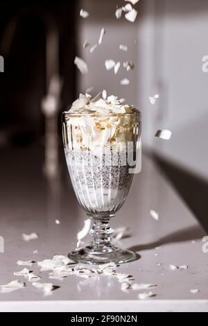Semi di Chia e budino di latte di cocco con patatine di cocco in un bicchiere. Colazione vegana sana Foto Stock