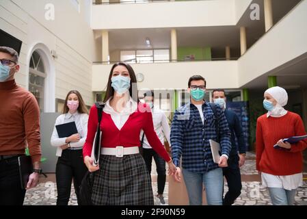 gruppo di studenti all'università che cammina e indossa la maschera facciale Foto Stock