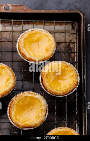 Pastel de Nata fresco cotto crema all'uovo portoghese Tart on griglia di raffreddamento Foto Stock