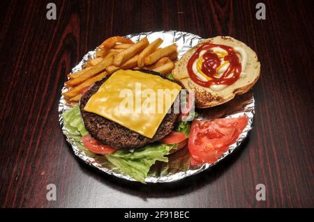 Delizioso cheeseburger con tutti i fissaggi su un panino Foto Stock