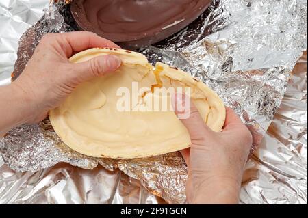 Uovo di Pasqua - primo piano di mani che rompono uova di cioccolato farcite fatte in casa. Vista dall'alto. Shot orizzontale. Foto Stock