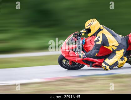 La pratica del motociclo che si appoggia in una curva veloce sulla pista Foto Stock