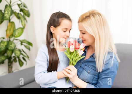 Buon giorno della madre. La figlia del bambino si congratula con le mamme e dà tulipani dei fiori Foto Stock