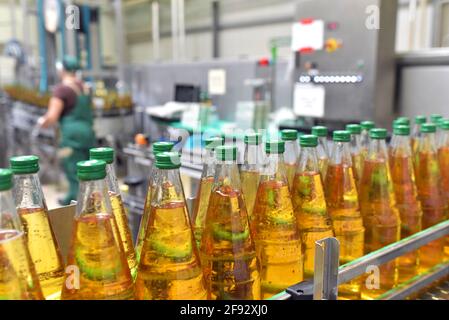 succo di mela in bottiglie di vetro in una fabbrica per l'industria alimentare - imbottigliamento e trasporto Foto Stock