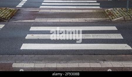 Zebra pedonale dipinta di bianco che attraversa una strada in Europa Foto Stock