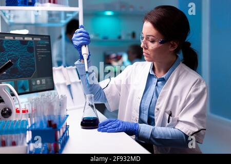 Lo scienziato preleva il campione con micropipetta indossando gli occhiali in un laboratorio moderno. Donna ricerca un nuovo esperimento in laboratorio moderno, analizzando il lavoro farmaceutico con attrezzature moderne.
