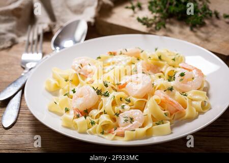 piatto di fettuccine di pasta con salsa alla crema e gamberi un tavolo di legno Foto Stock