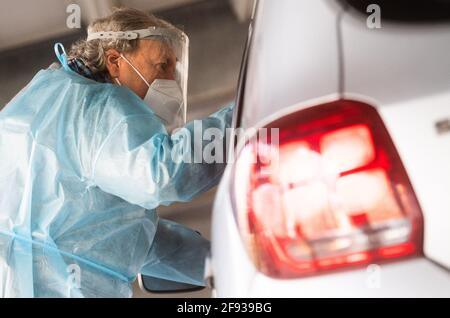 Hannover, Germania. 16 Apr 2021. Aiutanti a testare gli occupanti dell'auto al 'Test Center at the Zoo' con test rapidi per il nuovo virus corona. Il Robert Koch Institute (RKI) continua a segnalare un aumento delle nuove infezioni da corona in Germania. Credit: Julian Stratenschulte/dpa/Alamy Live News Foto Stock