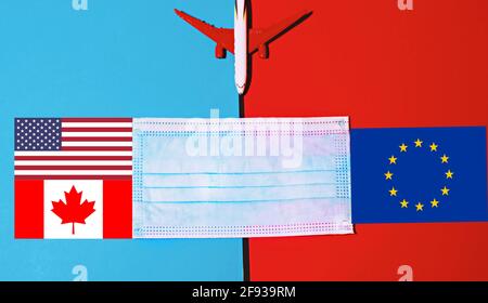 Vista dall'alto del modello di piano con maschera facciale .bandiere europee, statunitensi e canadesi. Concetto di viaggi sicuri . Foto Stock
