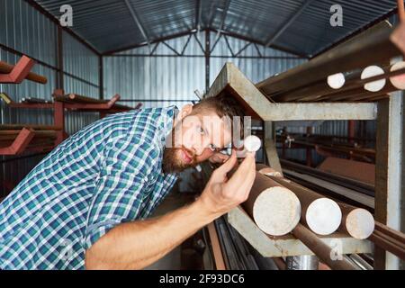 Operaio come impiegato specializzato di magazzino durante il controllo di qualità in il magazzino dei materiali della bottega del fabbro Foto Stock