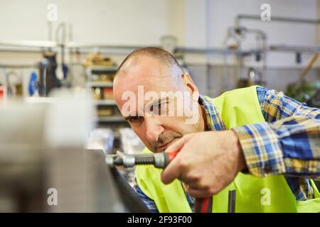 Fabbro o lavoratore di metallo lavora con morsetto a vite su a. banco da lavoro in officina Foto Stock